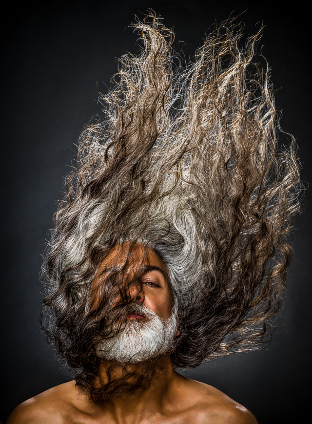 Portrait of a man with very long hair flipping it up over his head. © Dana Hursey Photography